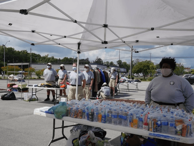 Volunteer booth/tent attendants behind tables with bottled water and clothing