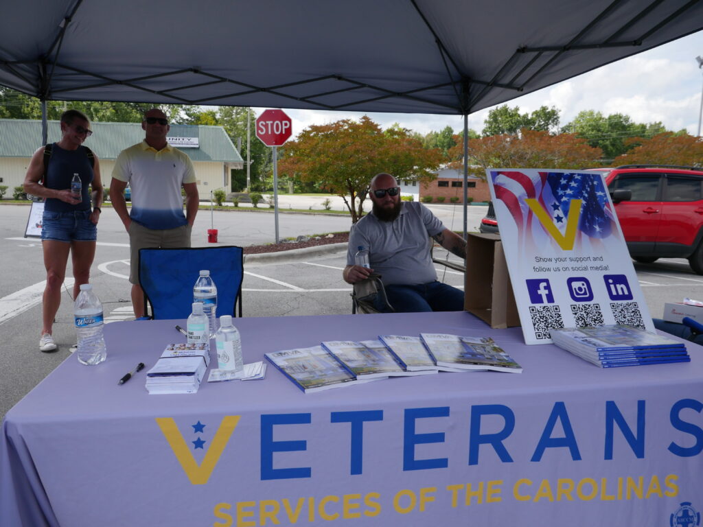Veterans Services of the Carolinas booth/tent with volunteers standing and sitting